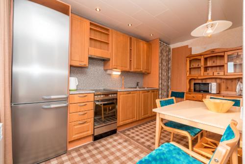 a kitchen with wooden cabinets and a table with chairs at Family apartments in Sortavala