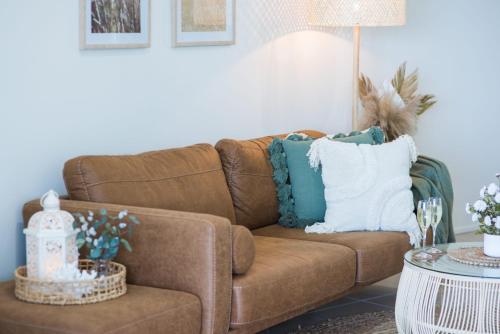 una sala de estar con un sofá marrón con almohadas azules y blancas en Bohemian Sunrise en Airlie Beach