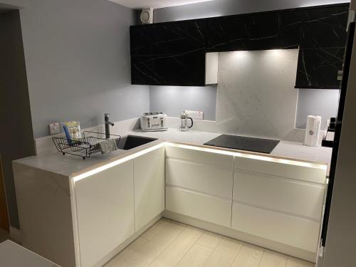 a kitchen with white cabinets and black appliances at Ocean Hideaway @ Portmore Bay in Portstewart