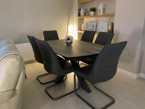 a dining room table with black chairs and a couch at Ocean Hideaway @ Portmore Bay in Portstewart