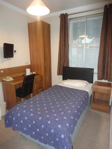 a bedroom with a bed and a desk and a window at Warwick Lodge in Kingston upon Thames