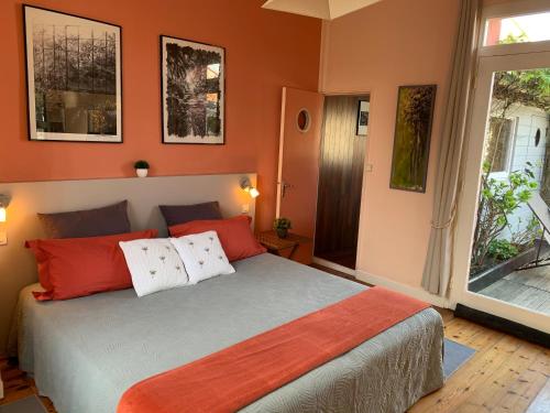 ラ・ロシェルにあるLe Patio maison de charme 150m plage et hyper centreのベッドルーム1室(オレンジ色の壁のベッド1台、窓付)