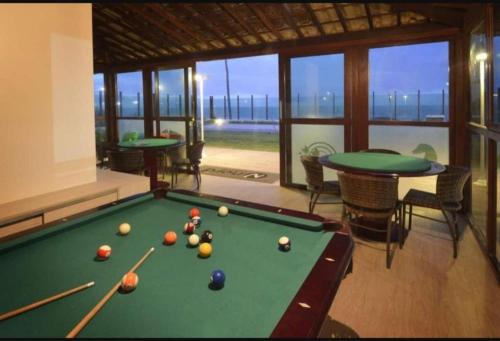 a billiard room with a pool table and two tables at Flat Tabatinga Nord, vista para o mar in Conde