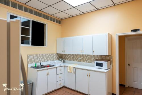 a kitchen with white cabinets and a microwave at Yellow Belly Backpackers in San Ignacio