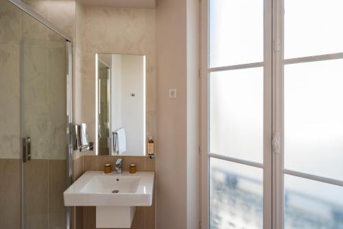 ein Badezimmer mit Waschbecken, Spiegel und Fenster in der Unterkunft Mercure Paris Opera Lafayette in Paris