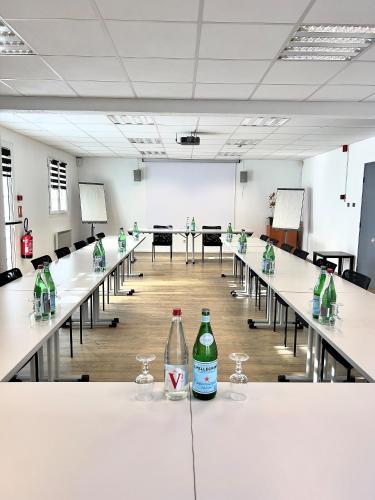 une salle remplie de tables avec des bouteilles de soda. dans l'établissement Kyriad Direct Reims Bezannes, à Reims