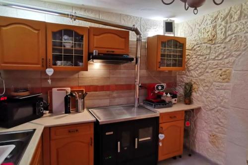 una pequeña cocina con armarios de madera y fregadero en 3 bedrooms villa with terrace and wifi at Acquaviva Platani, en Acquaviva Platani