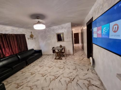 a living room with a couch and a large screen at CG Apartments Metro in Ikeja