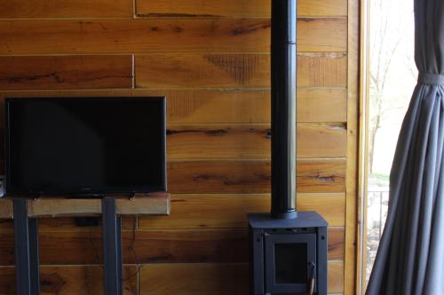 a television sitting on a stand next to a wood wall at Ayres del Champaqui Hotel Boutique Experiencial & Spa in Villa General Belgrano