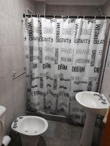 a bathroom with a shower curtain with a sink and a toilet at Monoambiente Claro de Luz in Federación