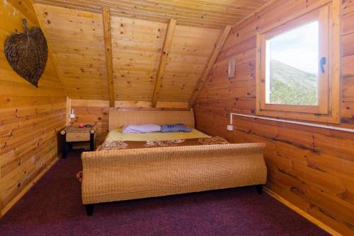 ein Schlafzimmer mit einem Bett in einem Blockhaus in der Unterkunft Lovcen mountain cottages in Vratnica