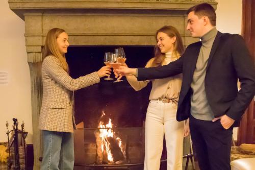 a group of people holding glasses of wine in front of a fireplace at Château-ferme des Abys in Paliseul