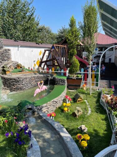 a miniature garden with pink flamingos and a pond at Qafqaz Fountain Villa in Gabala