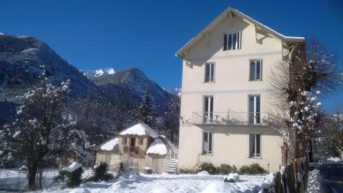 Un grand bâtiment blanc avec de la neige au sol dans l'établissement Le Relais des Cavaliers, à Villeneuve-dʼEntraunes