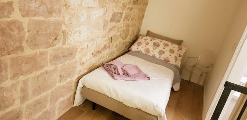 a bedroom with a brick wall and a bed with a pair of shoes at Appartamento Gattapone 9 in Gubbio