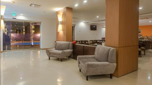 a lobby with two chairs and a reception desk at Staybridge Suites Guadalajara Expo by IHG in Guadalajara