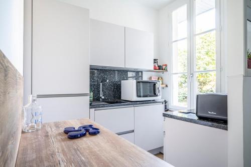 a kitchen with white cabinets and a wooden table at Studio cosy Hounau - Garage privatif in Pau