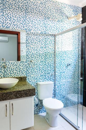 a bathroom with a toilet and a glass shower at Recanto do Village in Porto Seguro