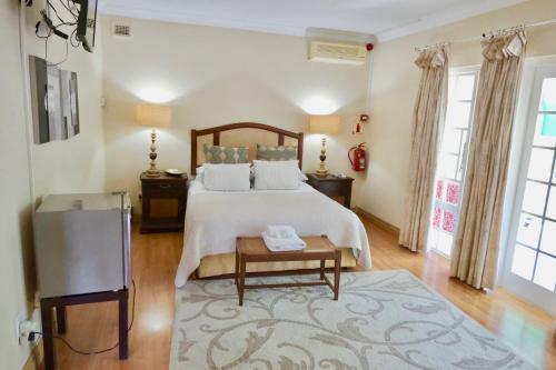 1 dormitorio grande con 1 cama y 1 mesa en The Whitehouse Bed and Breakfast, en Durban