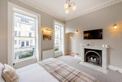 a white bedroom with a fireplace and a tv at Luxury Georgian Duplex in Central Bath in Bath