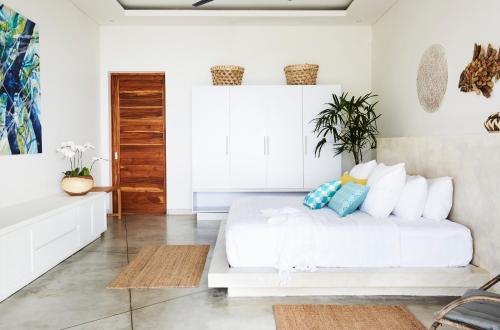 biała sypialnia z białym łóżkiem z poduszkami w obiekcie Villa Selalu w mieście Gili Gede