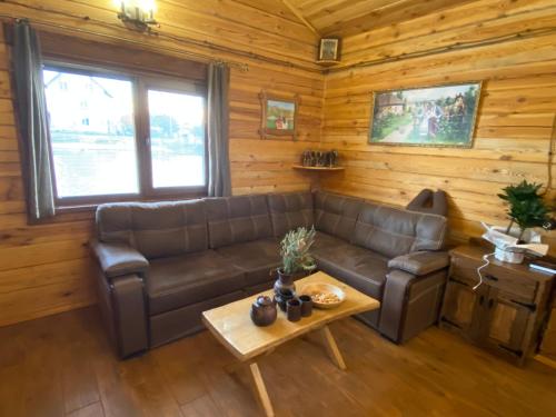 a living room with a leather couch and a table at Домик с баней на озере Мартышев in Kyiv