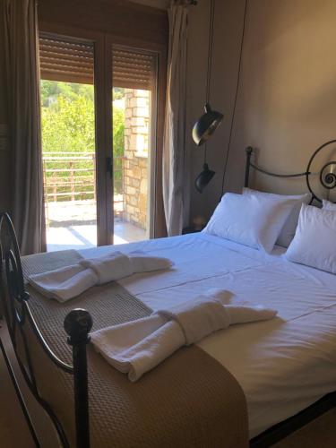 1 dormitorio con 1 cama con sábanas blancas y ventana en Luxurious Maisonette in the countryside with a pool, en Kalavrita