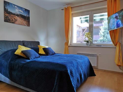 a bedroom with a bed with blue sheets and a window at Apartamentylove - Apartament Oliwia in Zakopane