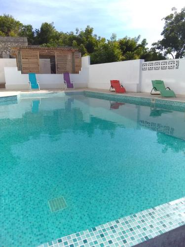 a swimming pool with blue water and colorful chairs at Residences Sommet Port Salut in Port-Salut