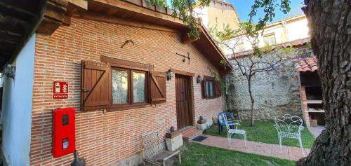 ein Backsteinhaus mit einem Fenster und Stühlen im Hof in der Unterkunft Algarabiastayingcristeta in Medina de Pomar