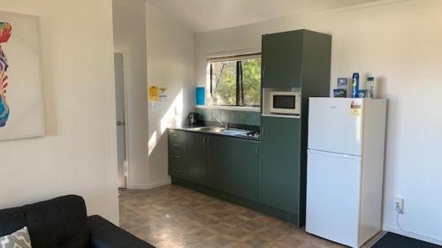 a kitchen with a white refrigerator and a window at Whatuwhiwhi TOP 10 Holiday Park in Tokerau Beach