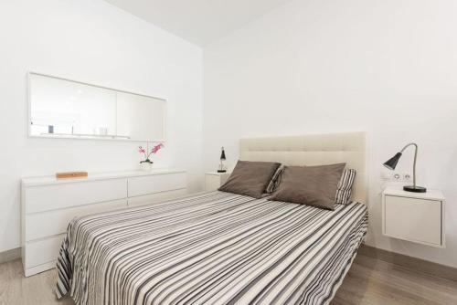 a white bedroom with a bed with a striped blanket at Charming loft B in Málaga