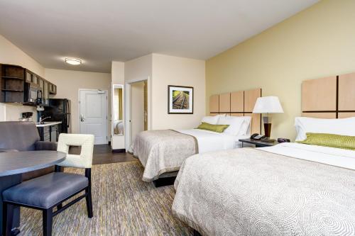 a hotel room with two beds and a desk at Candlewood Suites Cut Off - Galliano by IHG in Galliano