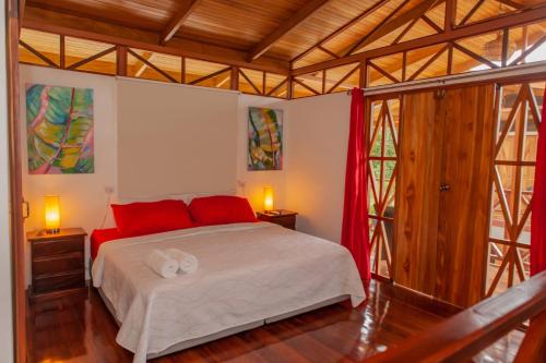 sypialnia z dużym łóżkiem z czerwonymi poduszkami w obiekcie Ibiza Tropical Beach Villas w mieście Uvita