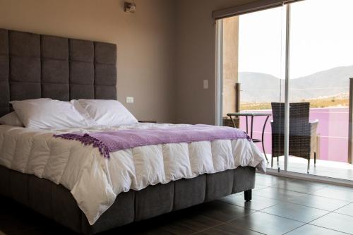 1 dormitorio con 1 cama grande y ventana grande en Flor de Cera en Valle de Guadalupe