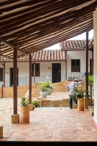a person standing under a patio with a building at Don Juan De Dios De Guane Hotel & Centro De Convenciones in Barichara