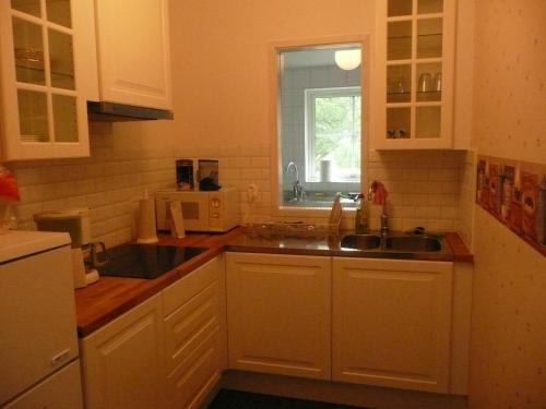 a kitchen with white cabinets and a sink and a window at Kullens Bed and Breakfast in Mellby