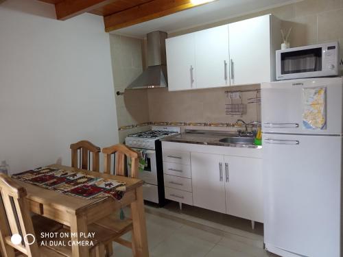 eine Küche mit weißen Schränken, einem Tisch und einem Waschbecken in der Unterkunft Apart Ruta 40 in El Chalten