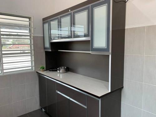 a kitchen with black cabinets and a counter top at Impiana Homestay Jitra in Jitra