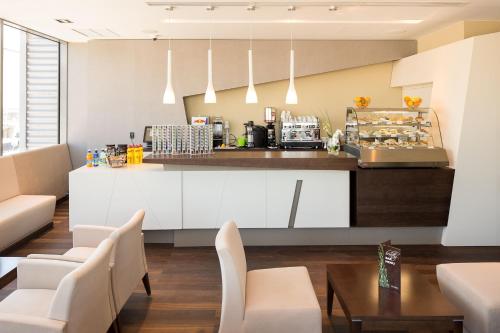 a kitchen with white cabinets and chairs and a counter at Kronwell Brasov Hotel in Braşov