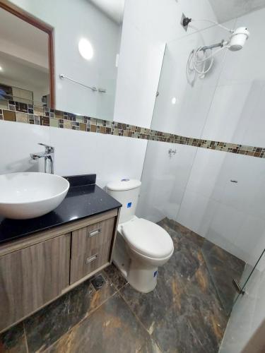 y baño con aseo, lavabo y espejo. en Apartaestudio Centro Comercial la Central, en Medellín