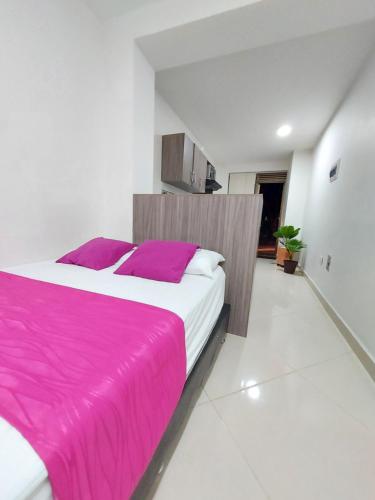 1 dormitorio con 1 cama grande con manta rosa en Apartaestudio Centro Comercial la Central, en Medellín