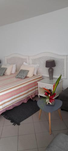Un dormitorio con una cama y una mesa con flores. en Studio pieds dans l'eau, en Le Gosier