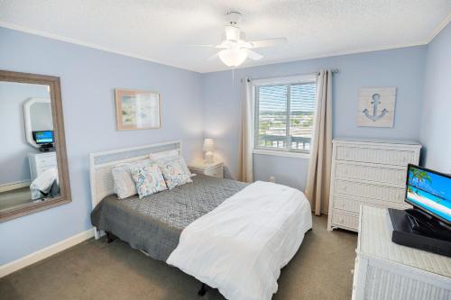 1 dormitorio con cama, espejo y TV en 2BR, 2Bath condo Oceanfront Getaway with pool, en Myrtle Beach