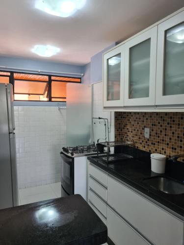 a kitchen with white cabinets and a black counter top at SUMMER HOUSE GENIPABU in Guarajuba