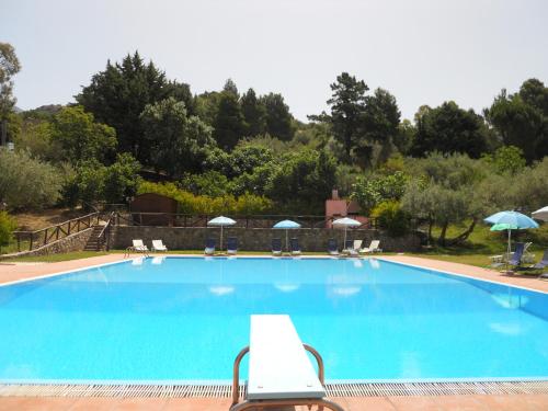 a large blue swimming pool with chairs and umbrellas at L'Antico Casale in Polizzi Generosa