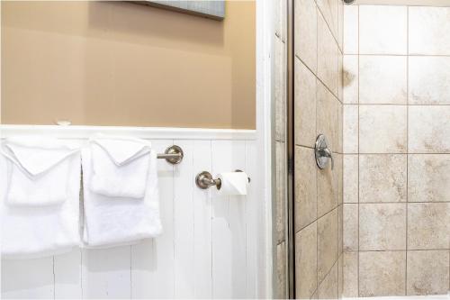 a bathroom with a shower and white towels at Hotel Louisbourg in Quebec City