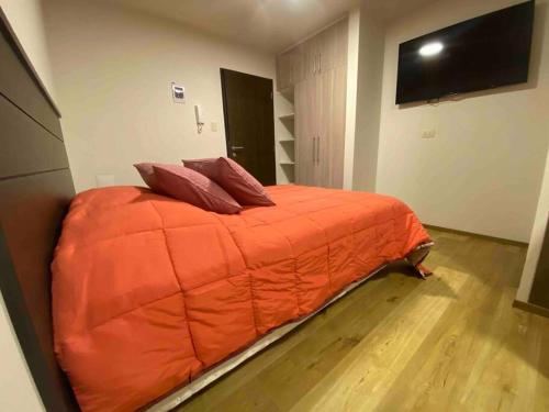 a bedroom with a large orange bed with two pillows at Smart studio in Cochabamba
