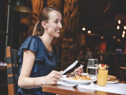 una mujer sentada en una mesa con un plato de comida en Hotel Louisbourg, en Quebec