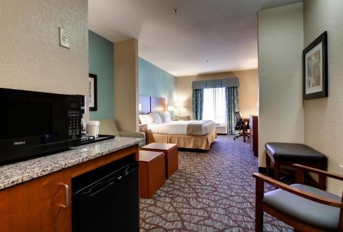 a hotel room with a bedroom with a bed and a television at Holiday Inn Express & Suites Jacksonville South - I-295 by IHG in Jacksonville